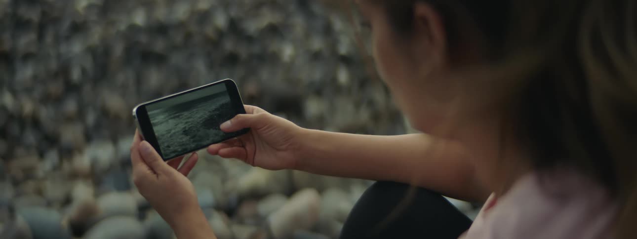 A woman records sea waves with her smart phone