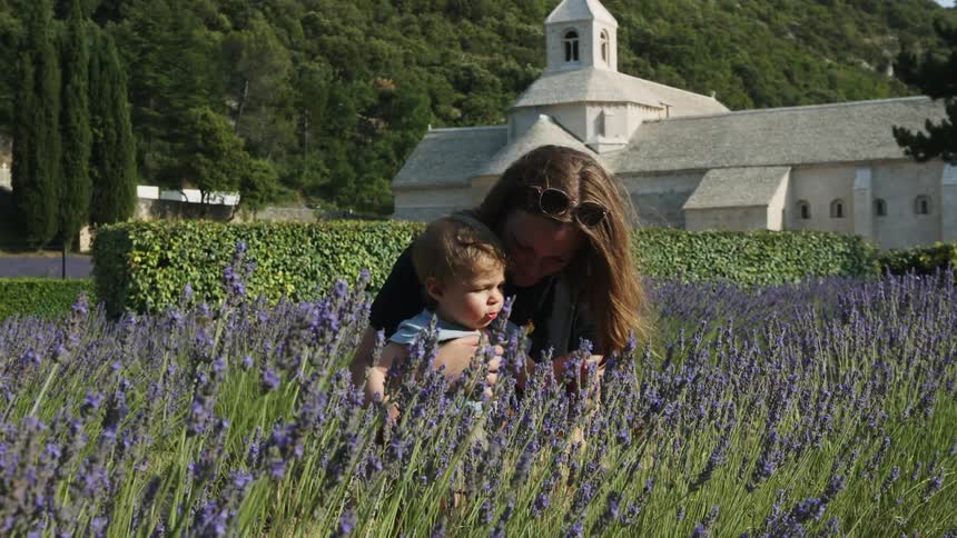 A woman sits with her son in a lavender field outside a church