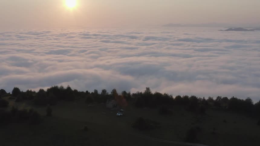 Clouds covering the landscape with a vehicle parked on a hill