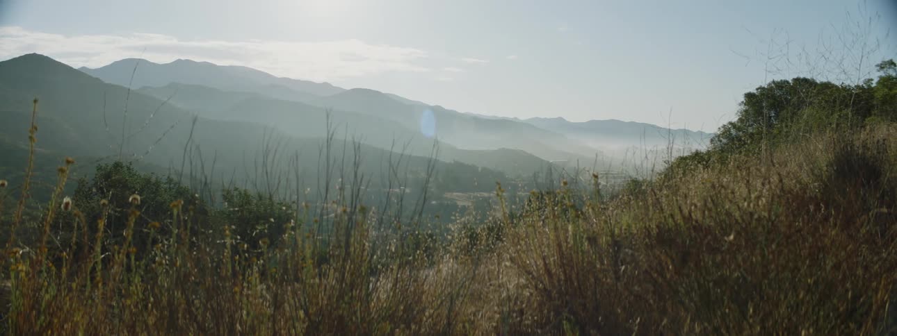 View of distant mountain range and misty valley seen from mountain slope at dawn