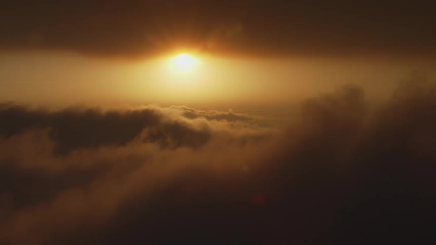 Aerial view of a the sun setting at golden our between the clouds