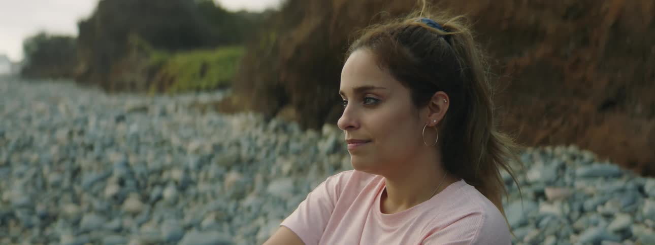 A woman stretching her neck and smiling while sitting outdoors in nature