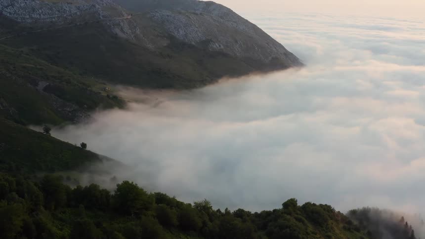 Aerial view of high mountain above white clouds