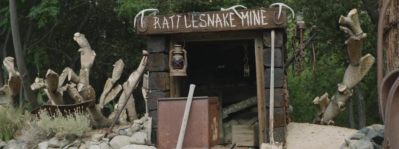 Plants and rocks are near the sign marking the entrance to rattlesnake mine
