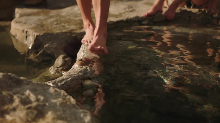 A person cross over the stream balancing on rocks