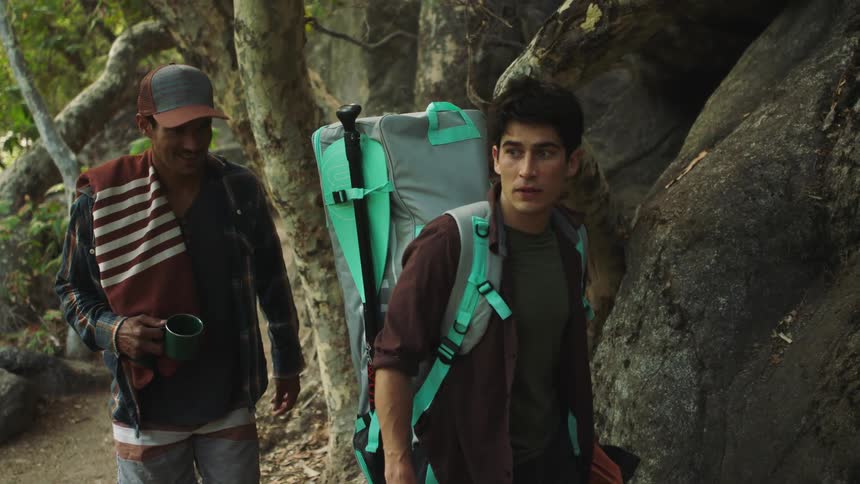 Two friends hiking a trail in the forest carrying a large camping backpack