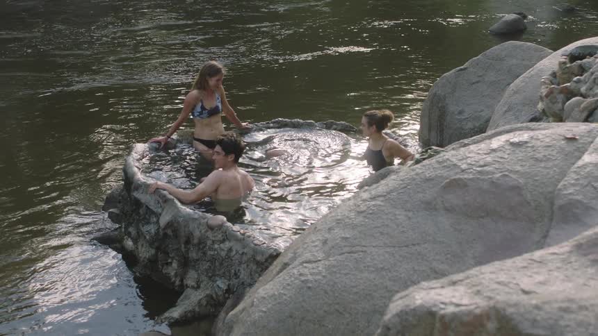 A small group of teens stand in a lake joking around and having fun