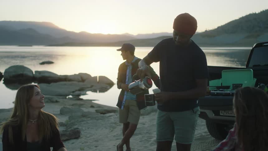 A man is pouring coffee by the lake