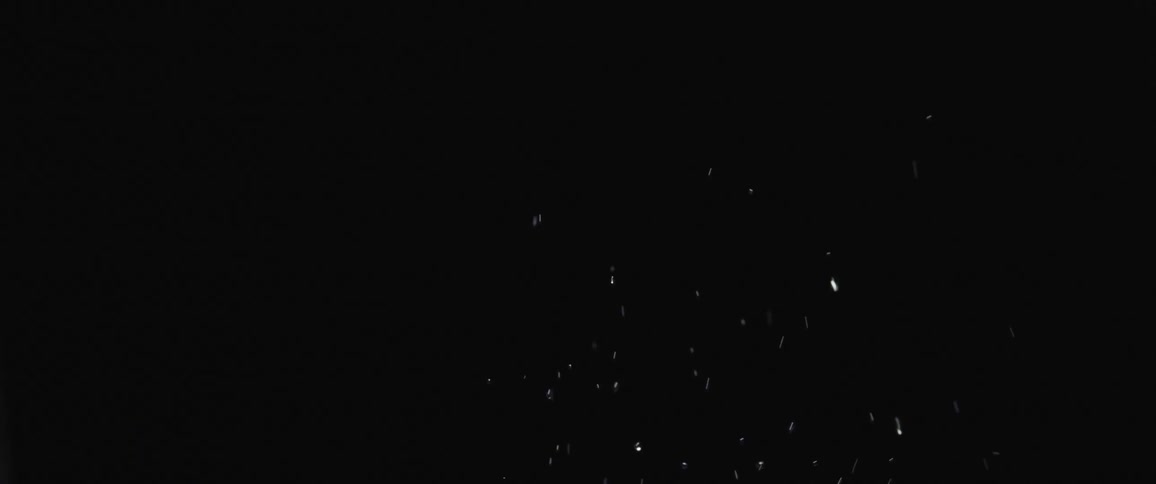 White chips of ice or water spray up and back down against a black background