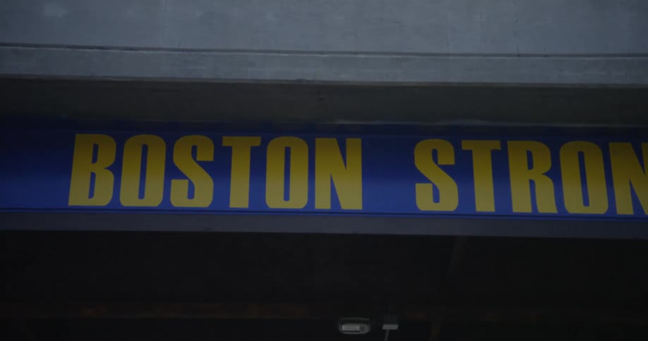 Blue banner with yellow letters hanging under a bridge at daytime