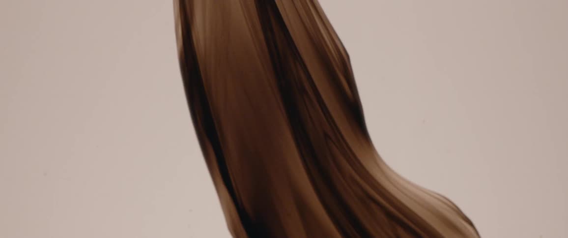 Flowing dark brown liquid on a white surface