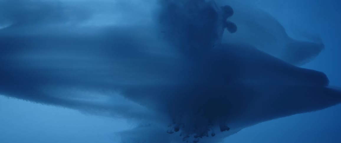 A highly magnified view of blue liquid is moving and swirling around in slow motion