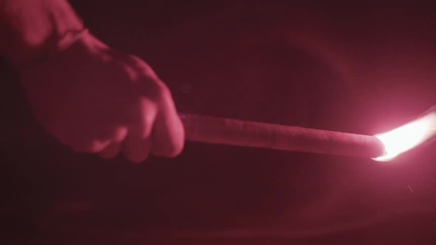 A person is walking in a dark area with a lit flare