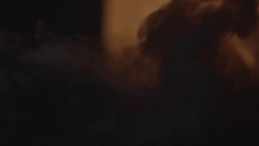 Smoke rises from a fire in a dark area