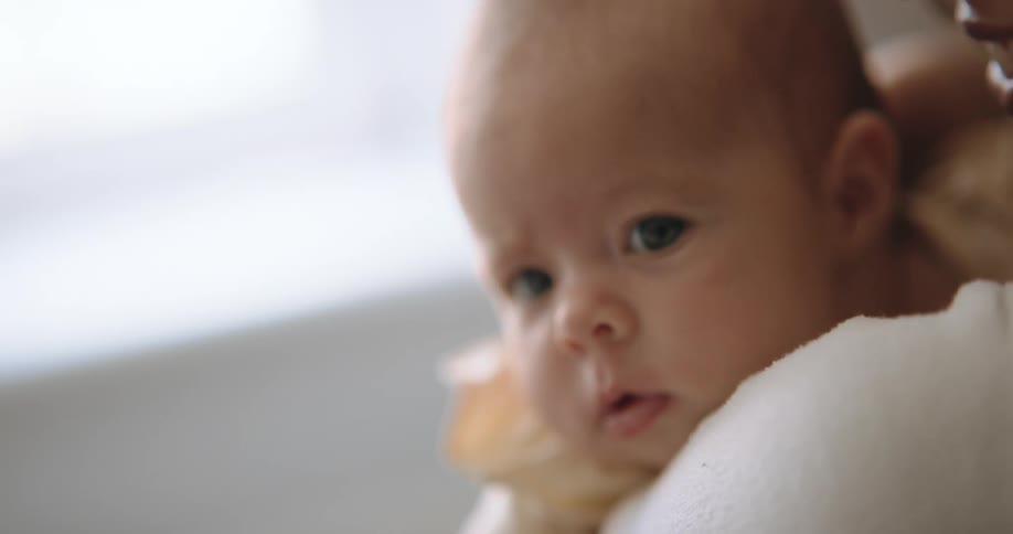 A mom smiles as she holds baby close head on her shoulder