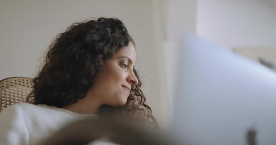 A teenage girl sits at home and looks to her side and smiles