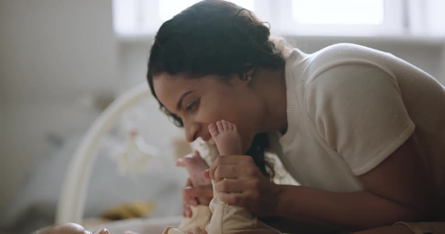 A woman kisses the bottom of her babys feet