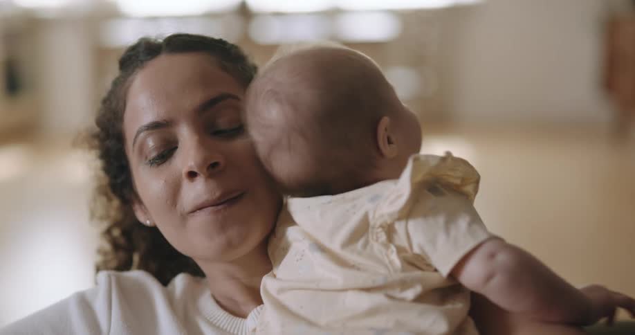 A woman struggles to eat cake while holding her infant