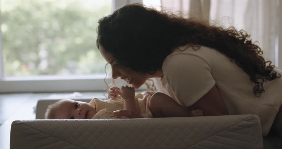 A woman kisses her babys stomach to make it laugh