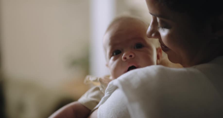 A woman rocks her yawning baby on her shoulder