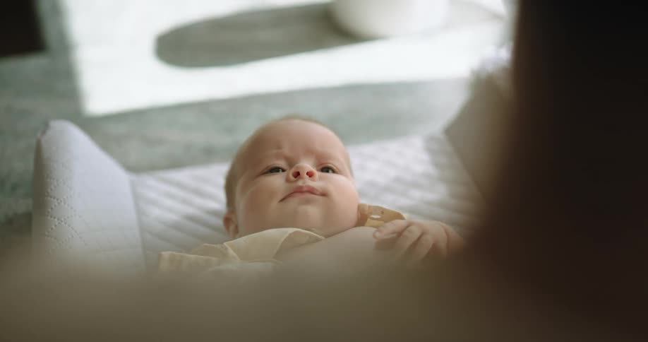 A woman is standing over her baby in a crib