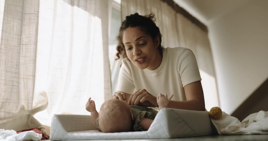 A mother talks to her baby as she dresses her