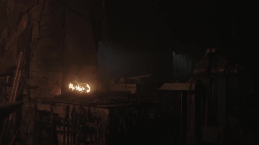 A fire blazes in a dark shop