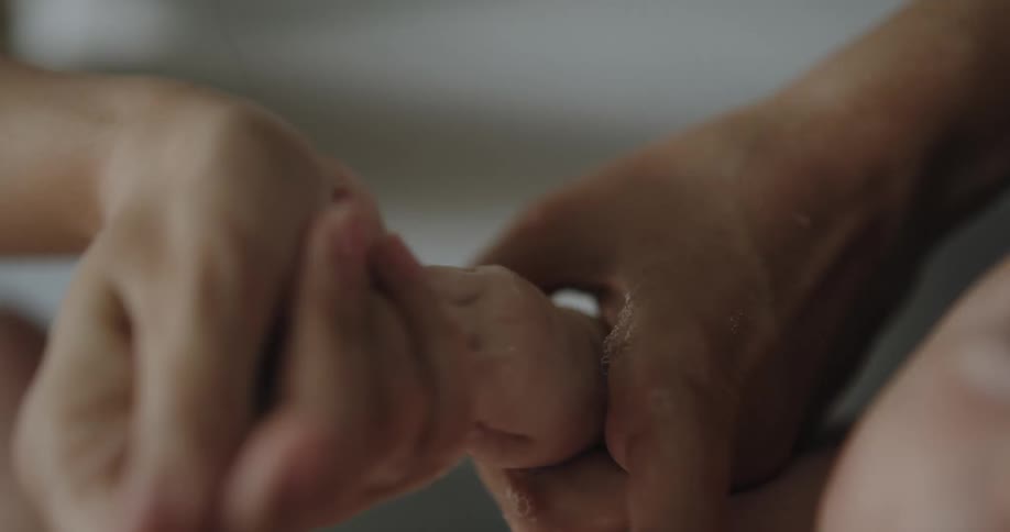 Mother carefully rinses babys hand during bath time