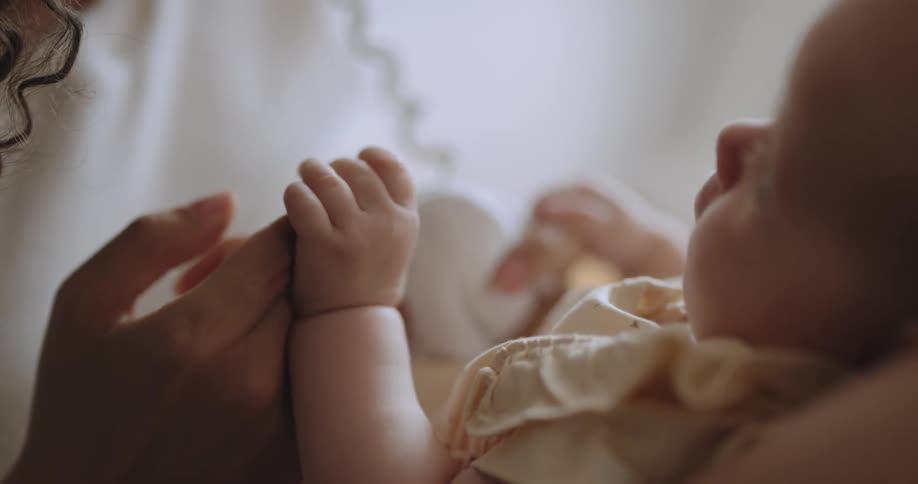 Mother smiles at baby as child holds her finger