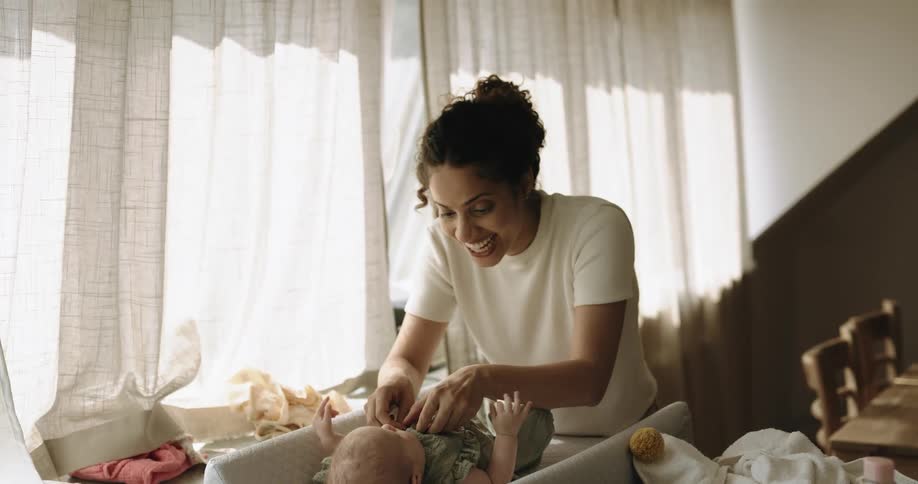 A mother is dressing her baby