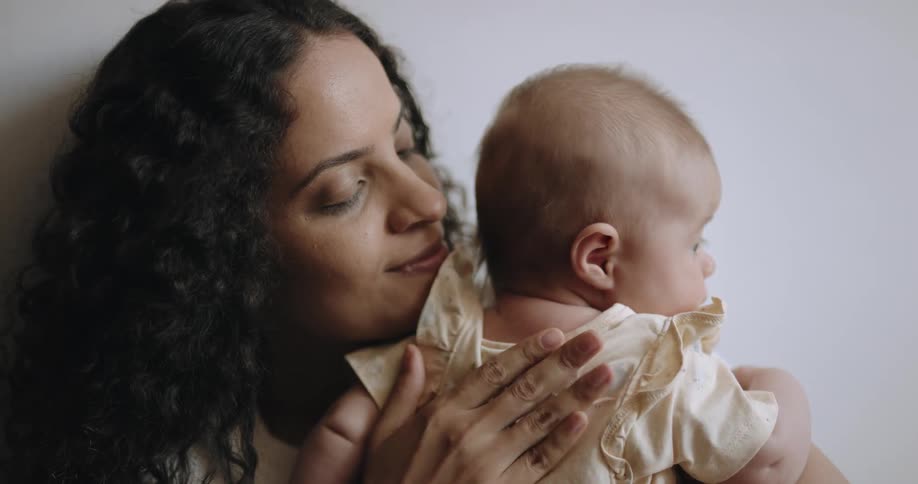 Mother smiles while holding baby and patting childs back