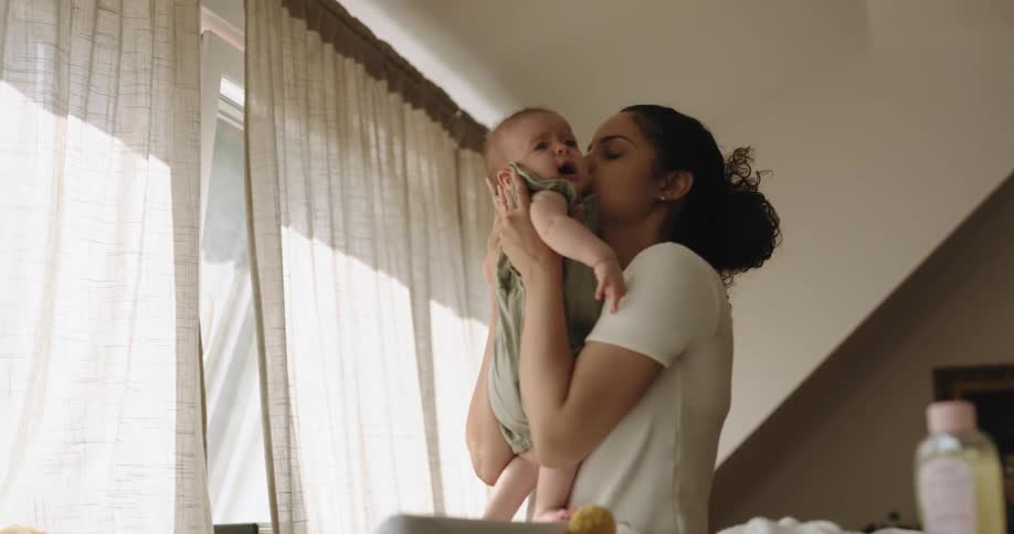 A mother picking up her infant daughter from a changing table