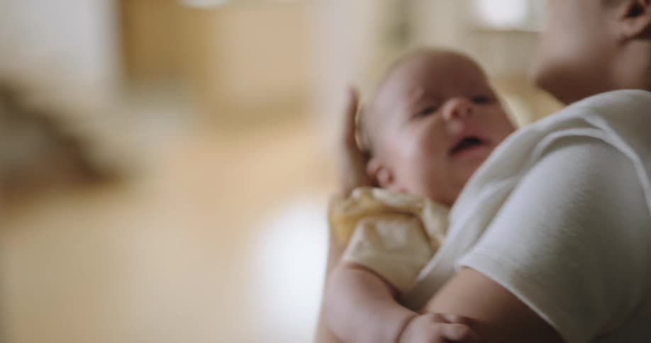 A woman is holding her baby and rocking them as they cry