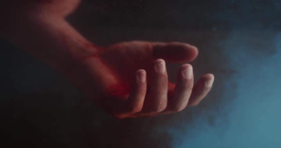 Bleeding hand floats unmoving in water as blood spreads