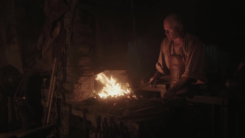 A man brushing a small fire with a poker