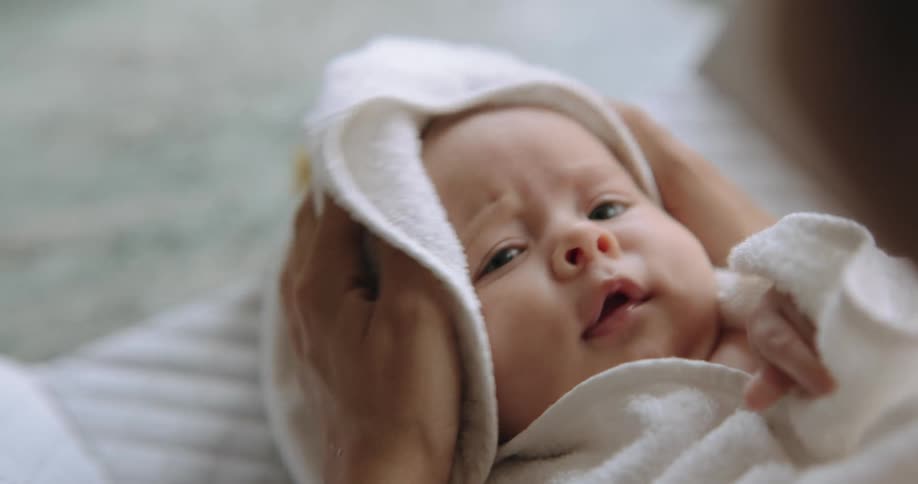 A woman dries her babys head with a towel