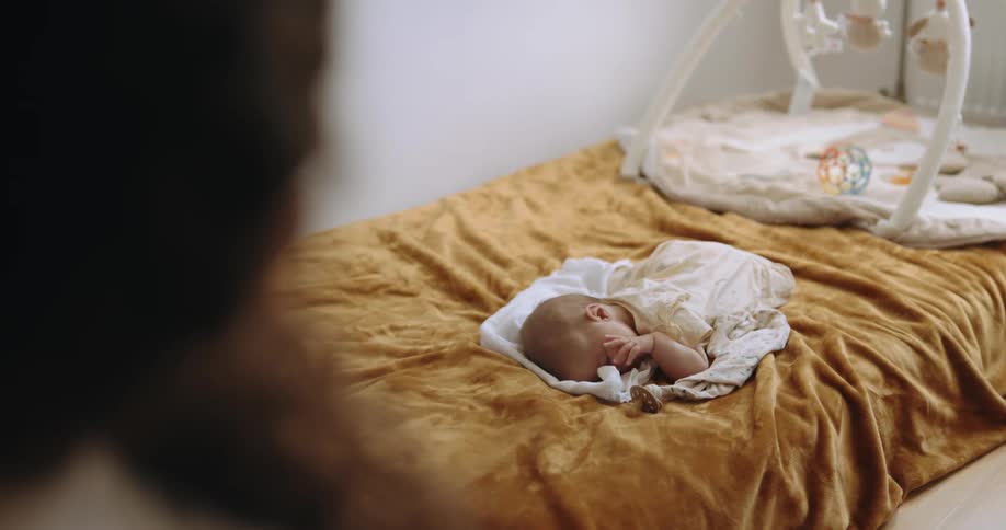 A woman watches a baby sleep