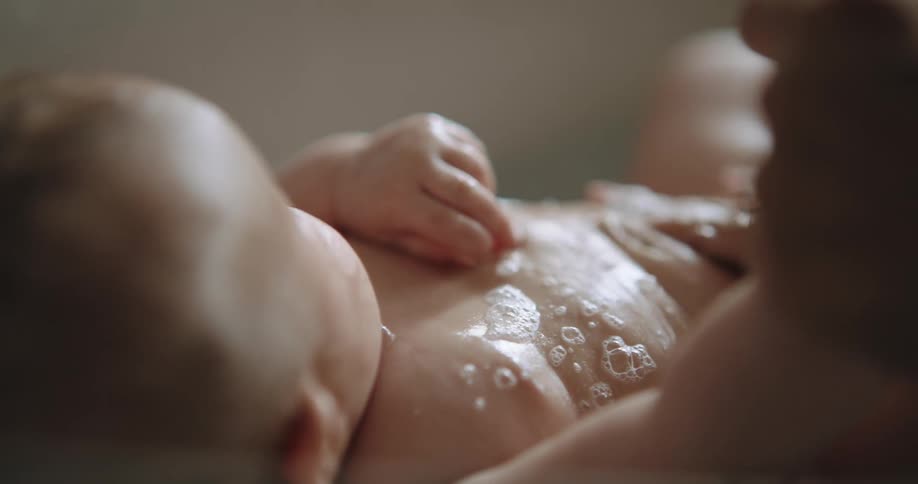 A baby is being bathed with soap and water