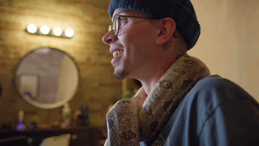A man is posing with a snake around his neck