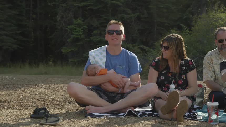 A family sits on blankets outside in the sunset