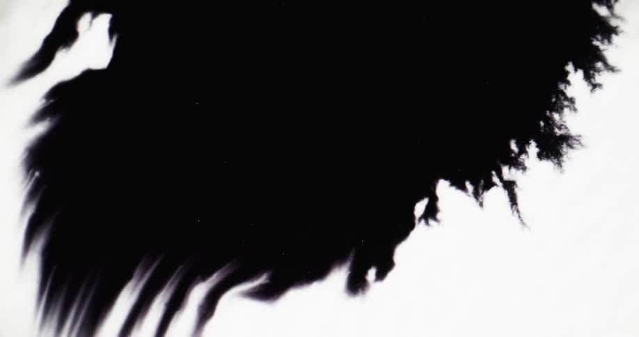 Black ink spreads further out on a white surface