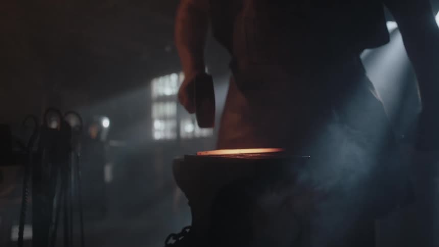 A blacksmith heats a rod then hammers it while it's hot