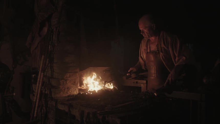 A blacksmith is stirring a fire