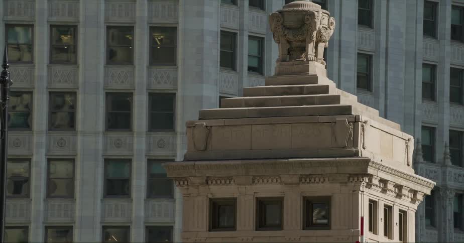 Carved urn tops building near street under skyscrapers