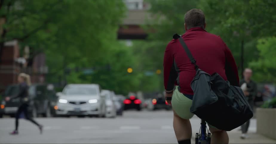 A man rides his bicycle down the busy street