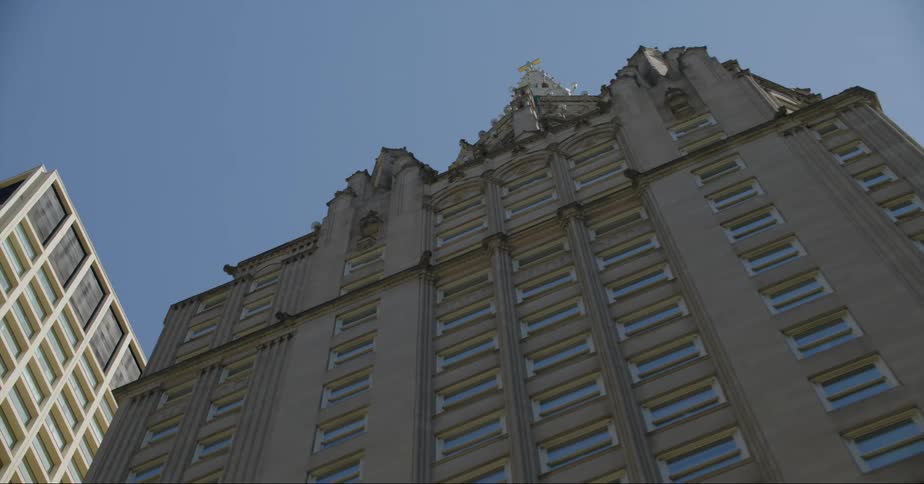 A stone building with a steeple towering overhead in a city