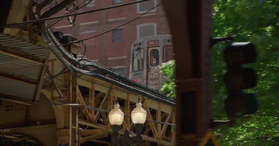 A passenger train travels on an elevated track through a city neighborhood