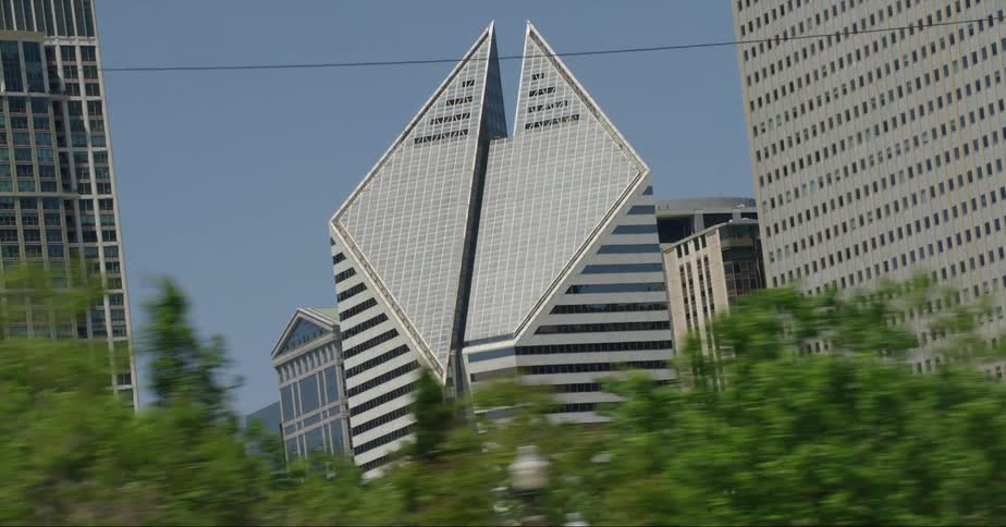 Traffic moves along street past skyscraper with slanted geometric top