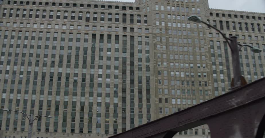 An iron bridge sits below an enormous building downtown