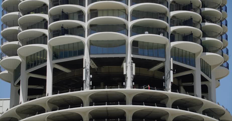 Apartment building with curved overhangs over each balcony has a parking garage at the base